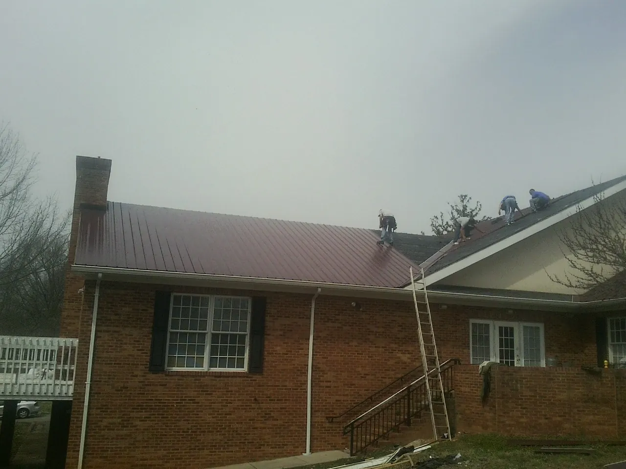 Crew setting red metal roofing panels on a brick home in Williamsport