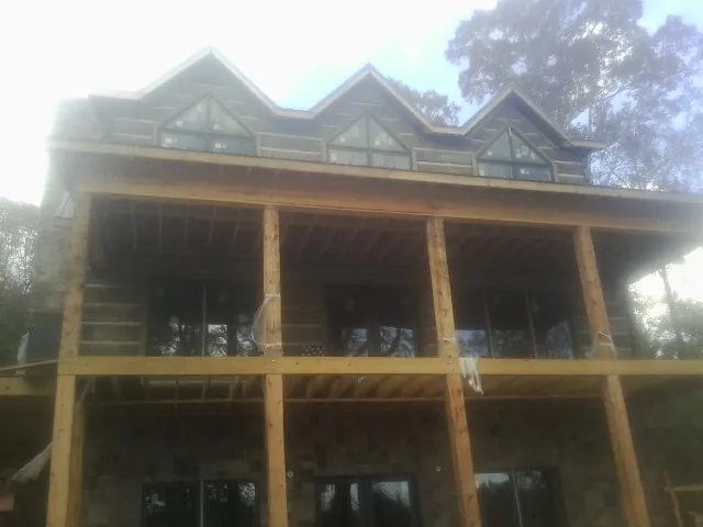 Dormers and porch framing on a large log home under construction — Roof Coating work by our crew in Williamsport