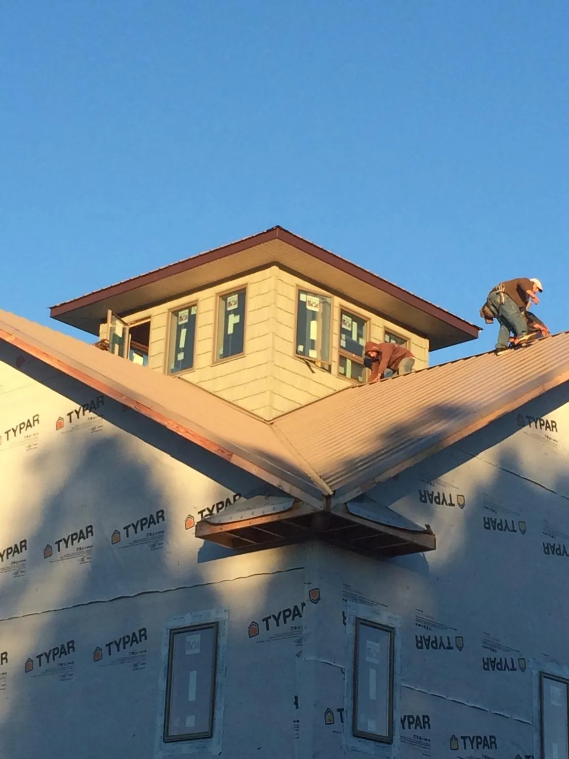 Roofers working around a rooftop cupola on a new metal roof at sunset — Roof Waterproofing in Williamsport by Roofing Brothers